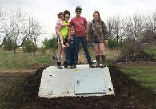 Family standing on top of a storm shelter.